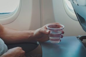 Hand holding a cup of water beside a cabin window